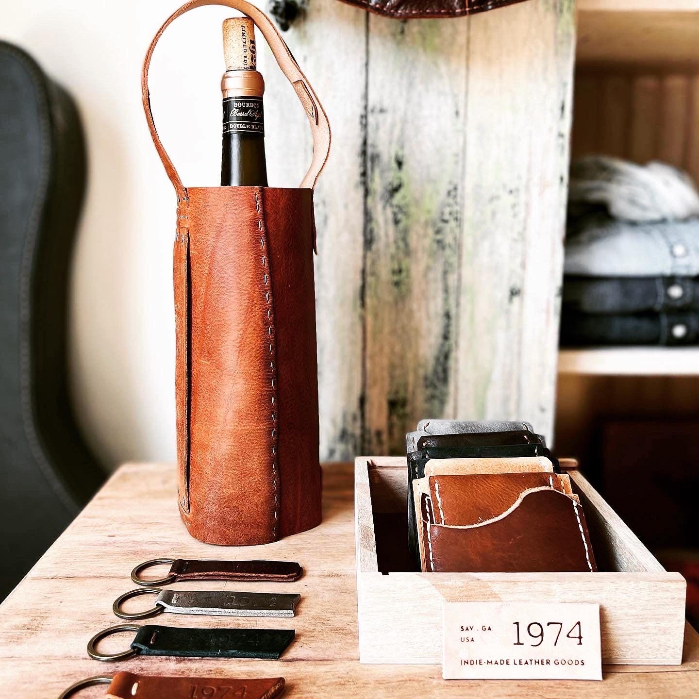 View of 1974 Leather Goods products including the Whiskey & Wine tote in Hickory, 1974 Key Fobs, and 1974 Lucas Wallets