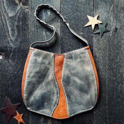 Birds eye view of the 1974 Beaufort River Tote in Smoke & Hickory on some dark wood with cut out leather stars