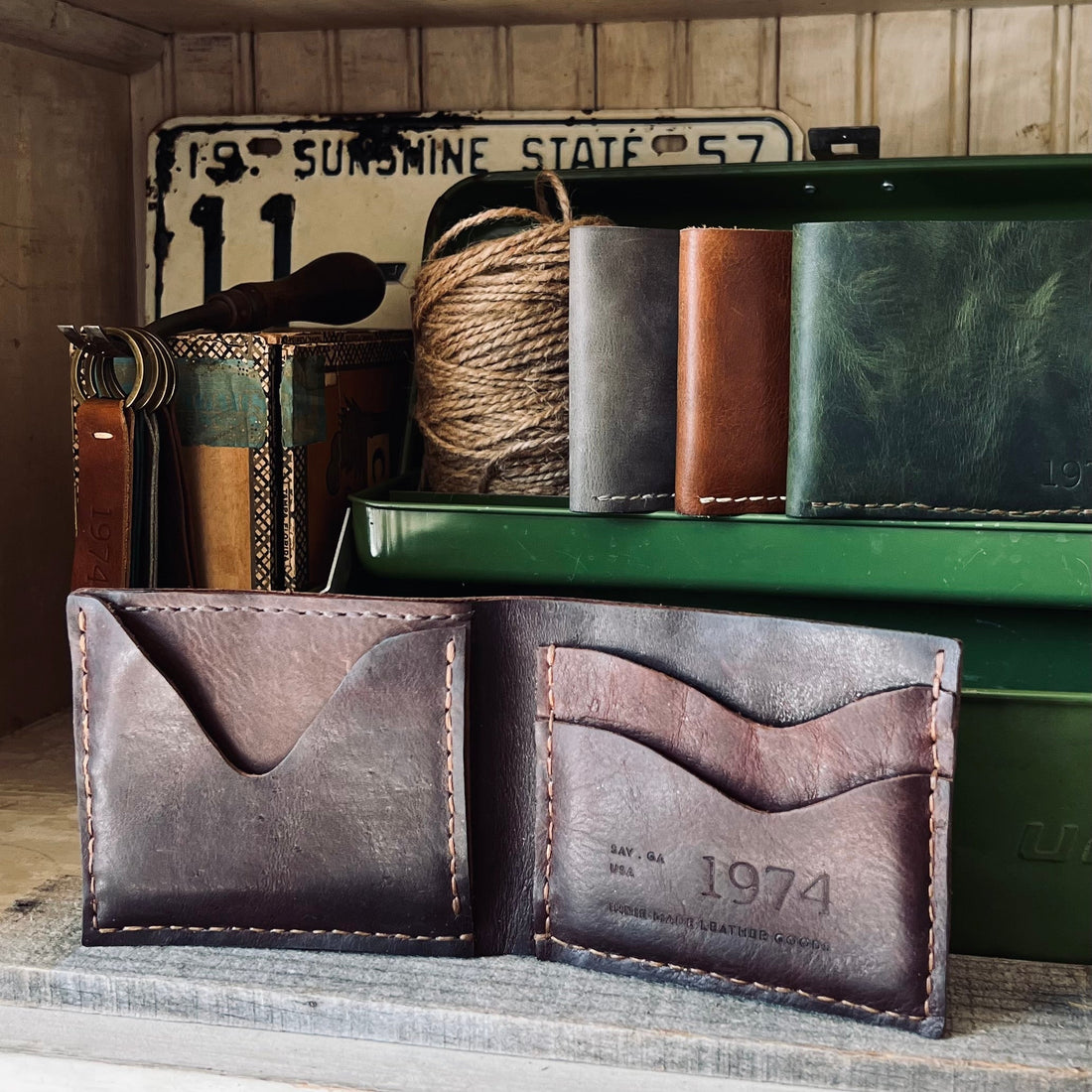 1974 Finnegan Leather Wallet in Chestnut sitting in a cabinet with other wallets and antiques