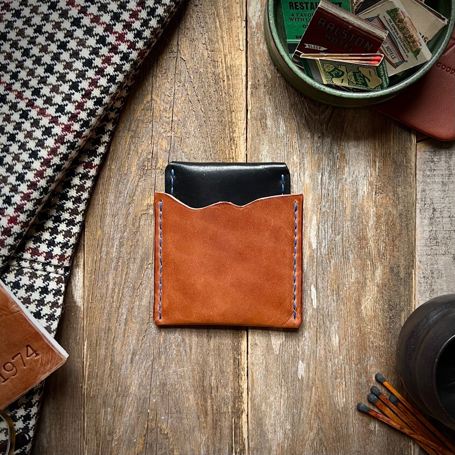 Stack of one of a kind leather Lucas Slim Wallets lying on a wooden table.