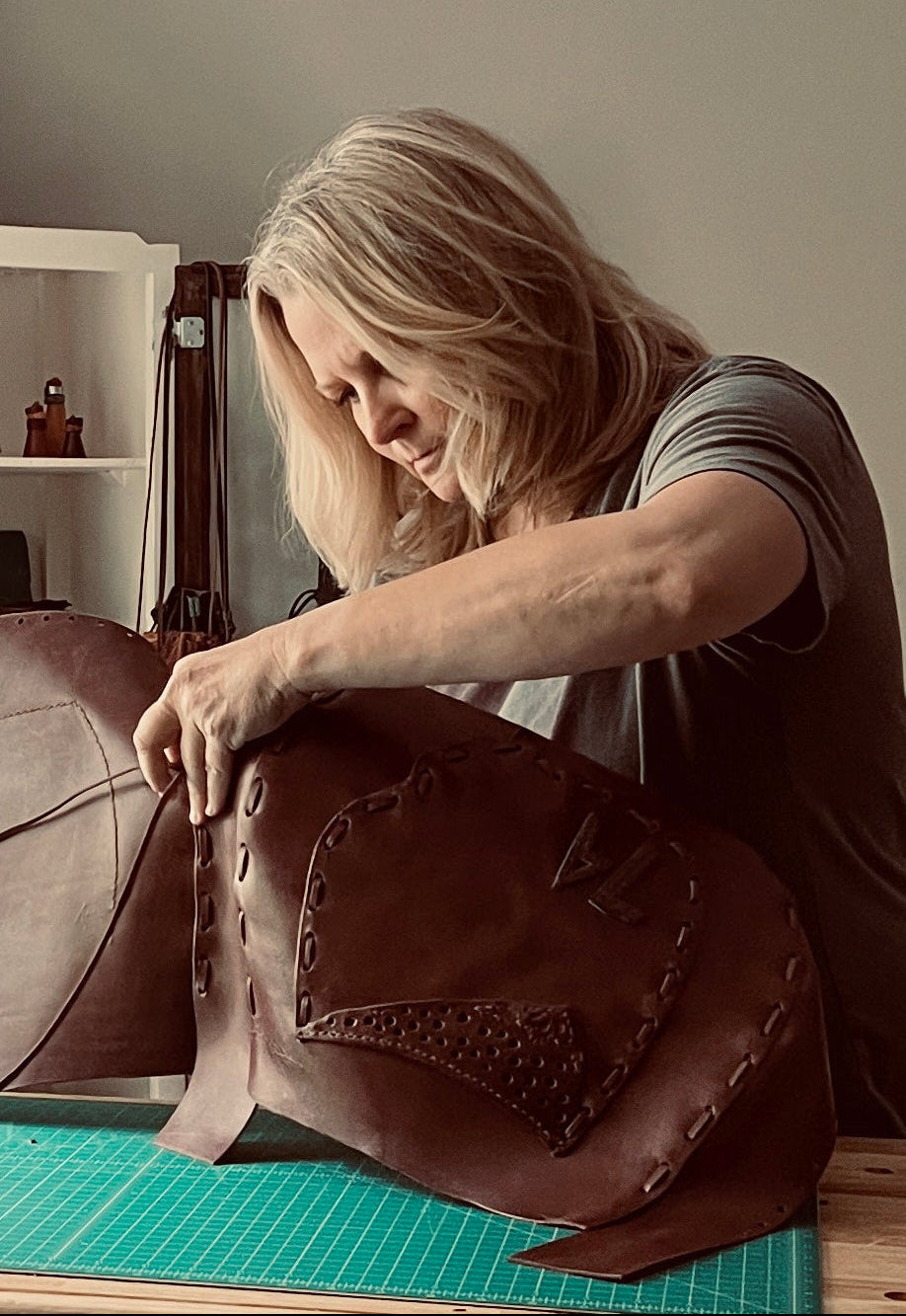 Aritsan Beth Dryden working on a leather bag in a workshop setting