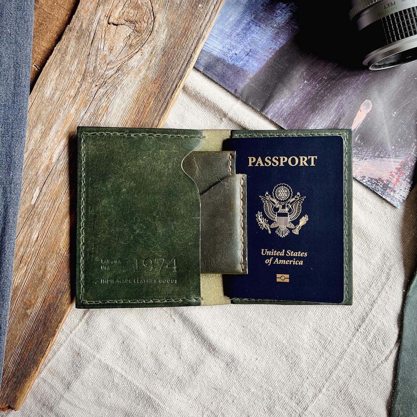 Wyatt Passport Holder in Pine layered with the Lucas Wallet and sitting on a wooden/canvas backdrop